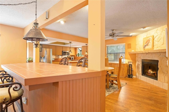 kitchen featuring appliances with stainless steel finishes, a textured ceiling, ceiling fan, and light hardwood / wood-style floors