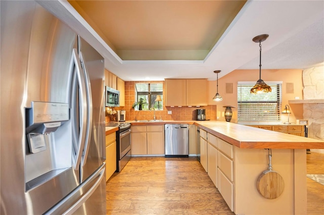 kitchen featuring appliances with stainless steel finishes, light hardwood / wood-style floors, kitchen peninsula, sink, and light brown cabinets