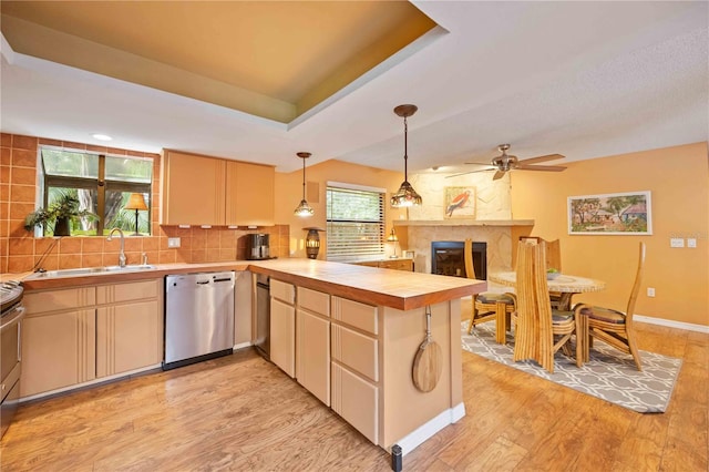 kitchen with appliances with stainless steel finishes, light hardwood / wood-style floors, kitchen peninsula, ceiling fan, and decorative backsplash