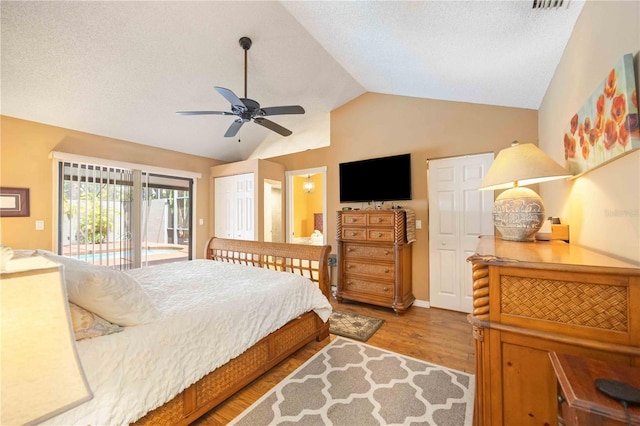 bedroom with a textured ceiling, hardwood / wood-style floors, access to exterior, lofted ceiling, and ceiling fan