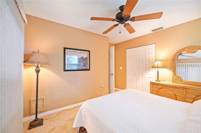 bedroom featuring a closet, ceiling fan, carpet, and a textured ceiling