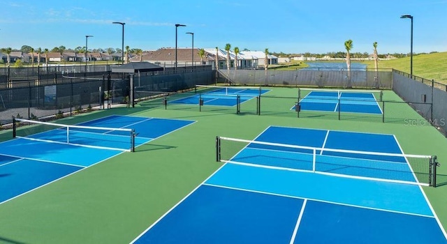 view of tennis court featuring community basketball court, fence, and a residential view