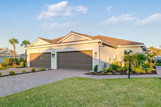 view of front of home featuring decorative driveway, a tile roof, stucco siding, a garage, and a front lawn