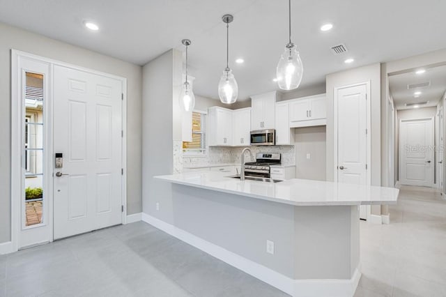 kitchen with stainless steel appliances, a sink, visible vents, light countertops, and decorative backsplash