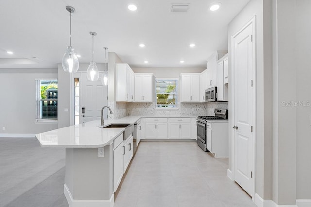 kitchen with stainless steel appliances, tasteful backsplash, a peninsula, and light countertops