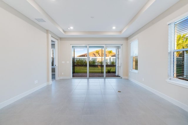 spare room featuring recessed lighting, a raised ceiling, baseboards, and light tile patterned floors