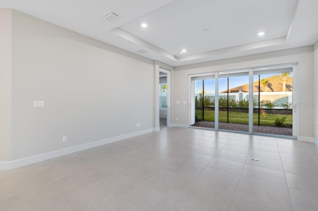 spare room with baseboards, a raised ceiling, visible vents, and recessed lighting