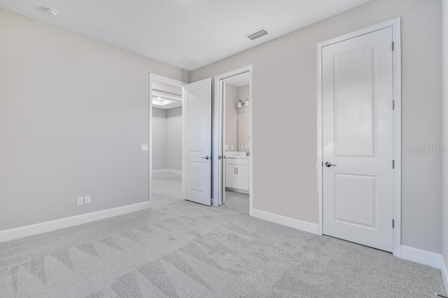 unfurnished bedroom featuring baseboards, visible vents, connected bathroom, and light colored carpet