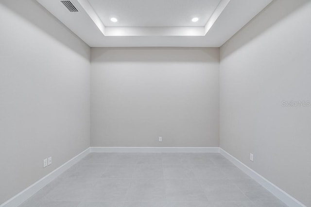 empty room featuring a tray ceiling, recessed lighting, visible vents, and baseboards