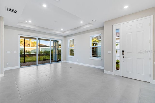 foyer entrance with a wealth of natural light, a tray ceiling, visible vents, and recessed lighting