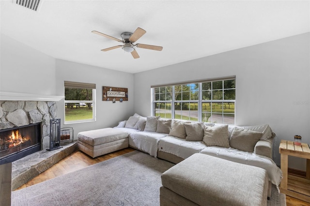 living room featuring a healthy amount of sunlight, ceiling fan, hardwood / wood-style floors, and a fireplace