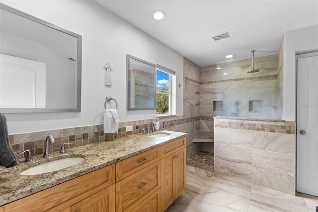 bathroom with backsplash, a tile shower, and vanity