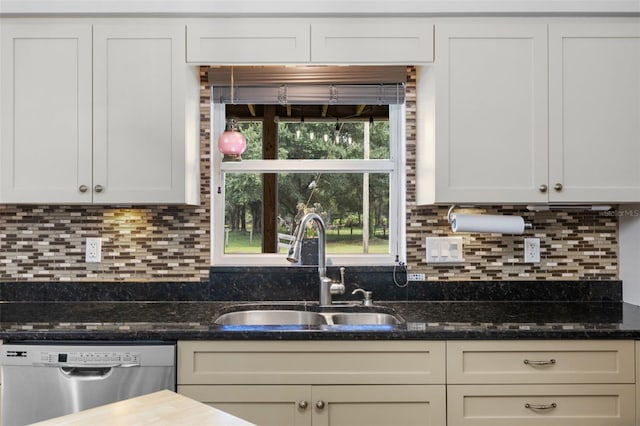 kitchen featuring stainless steel dishwasher, dark stone countertops, sink, and backsplash