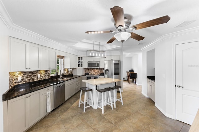 kitchen featuring appliances with stainless steel finishes, a kitchen bar, a center island, sink, and ceiling fan