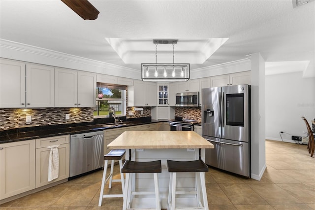 kitchen with hanging light fixtures, a center island, stainless steel appliances, tasteful backsplash, and ornamental molding