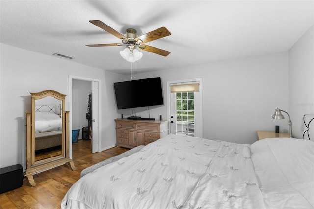 bedroom with hardwood / wood-style flooring, a walk in closet, and ceiling fan