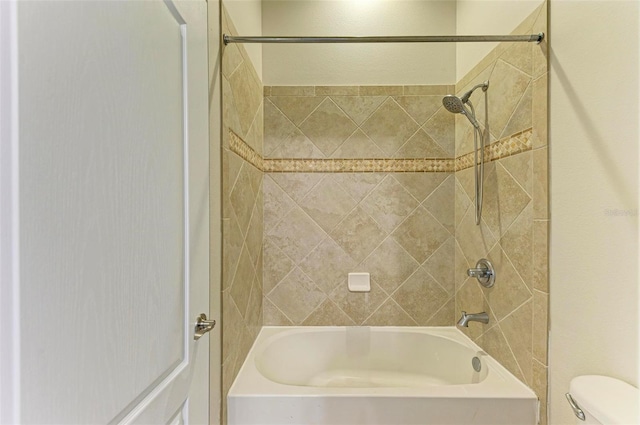 bathroom featuring tiled shower / bath combo and toilet