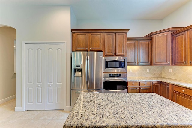 kitchen with a center island, light stone countertops, appliances with stainless steel finishes, and tasteful backsplash