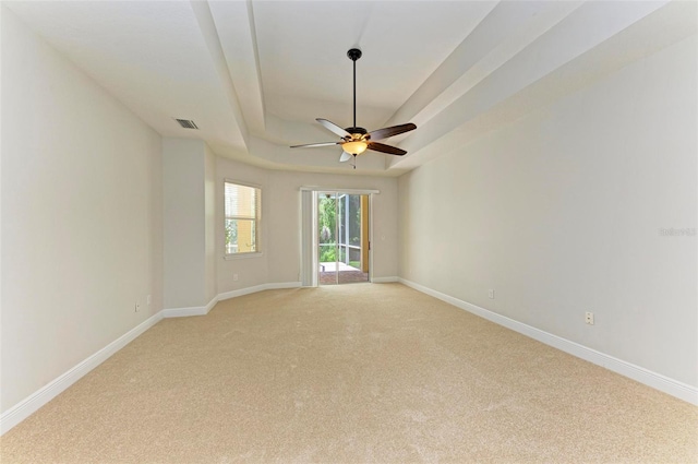 unfurnished room with light carpet, a raised ceiling, and ceiling fan