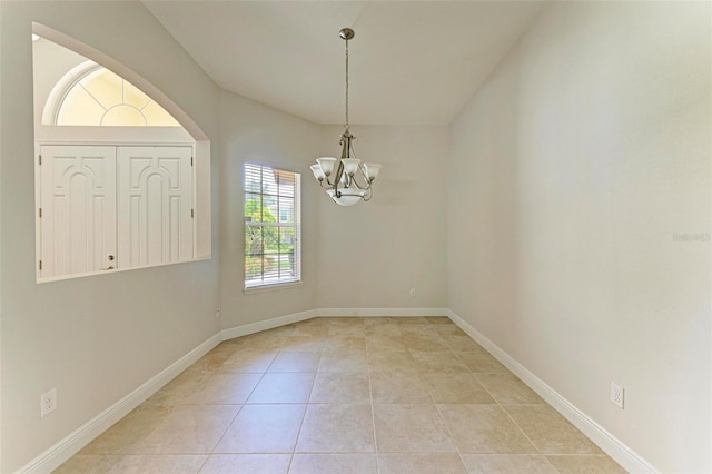 tiled empty room featuring a notable chandelier