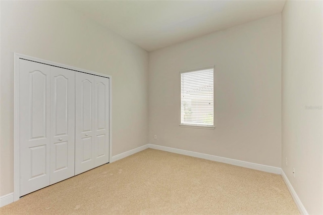 unfurnished bedroom with a closet and light colored carpet