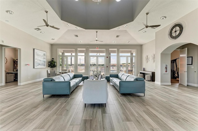 living room featuring a raised ceiling, light hardwood / wood-style flooring, and a towering ceiling