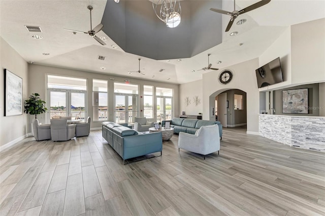 living room with a towering ceiling, light hardwood / wood-style floors, an inviting chandelier, and plenty of natural light