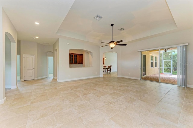 unfurnished living room with a tray ceiling, ceiling fan, and light tile patterned flooring