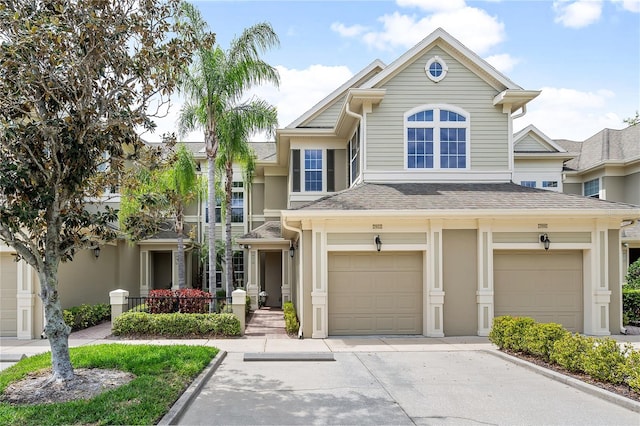 view of front of property with a garage, roof with shingles, driveway, and stucco siding