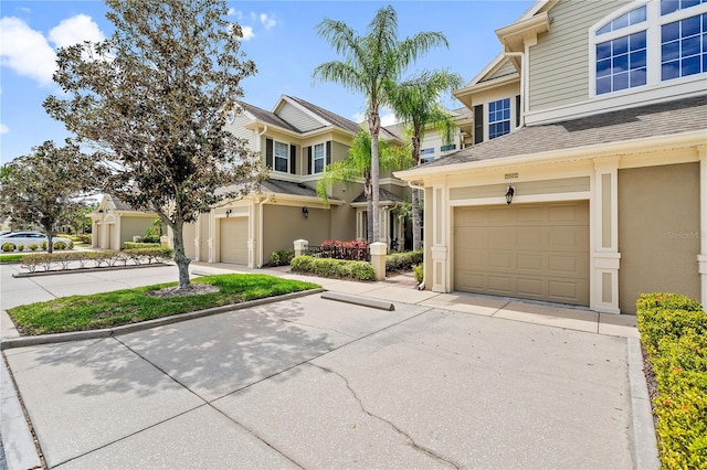 view of front of property featuring a garage, a shingled roof, concrete driveway, and stucco siding