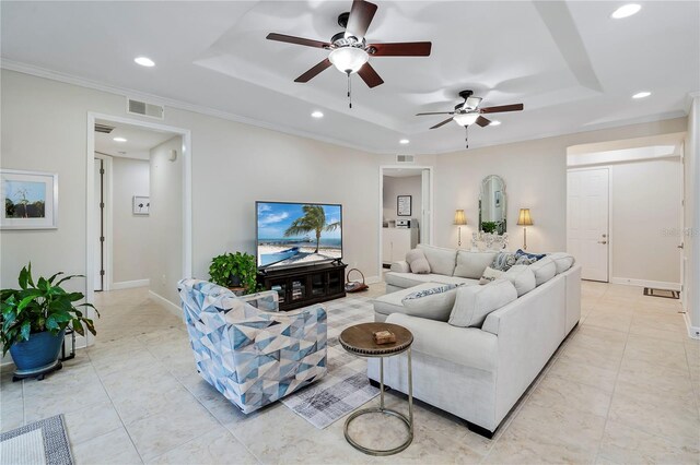 living room with crown molding, ceiling fan, and a tray ceiling