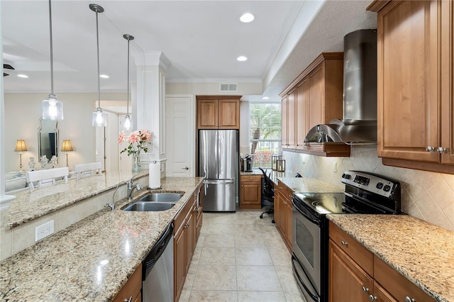 kitchen featuring stainless steel appliances, wall chimney exhaust hood, a sink, and brown cabinets