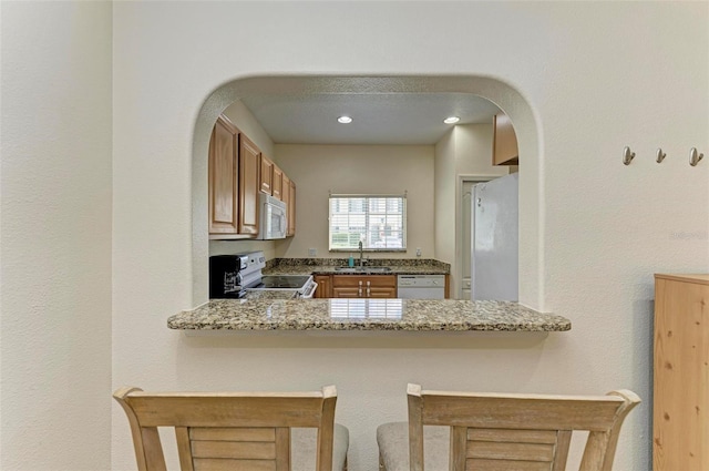 kitchen featuring white appliances, kitchen peninsula, and sink