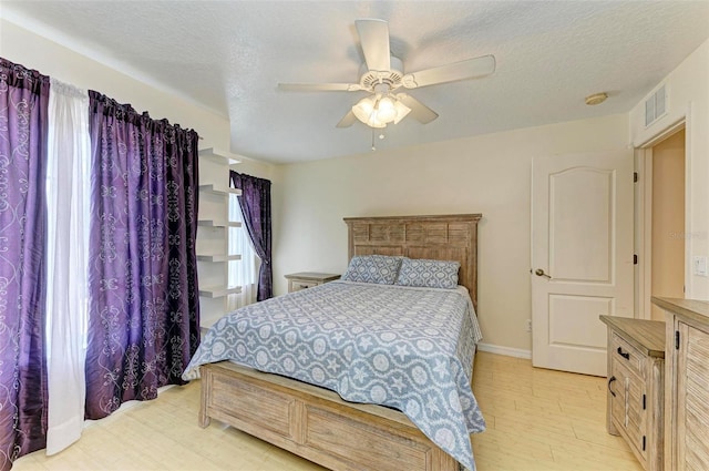 bedroom with ceiling fan, light hardwood / wood-style floors, and a textured ceiling