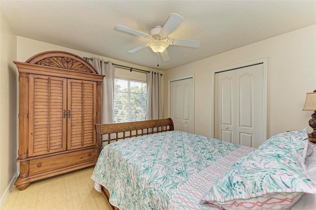 bedroom with two closets, ceiling fan, and light hardwood / wood-style flooring