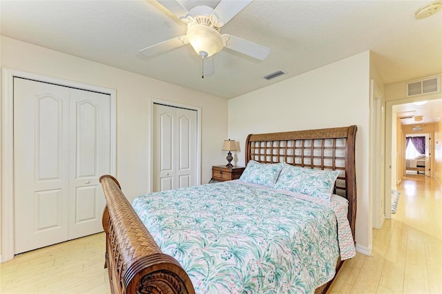 bedroom featuring ceiling fan, multiple closets, and light hardwood / wood-style floors