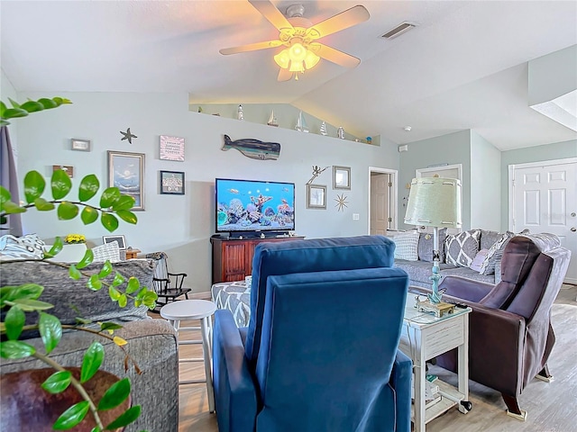 living area featuring a ceiling fan, visible vents, vaulted ceiling, and light wood-type flooring
