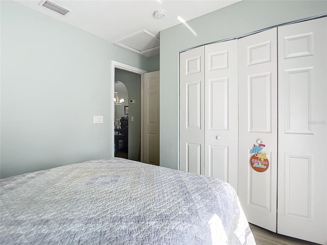 bedroom with visible vents, wood finished floors, and a closet