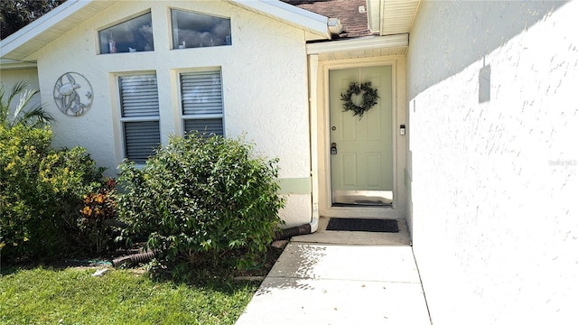 view of exterior entry featuring stucco siding and roof with shingles