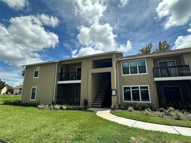 view of front of property featuring a balcony and a front yard