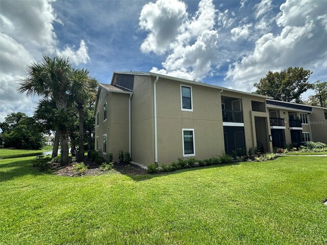 rear view of property featuring a balcony and a lawn