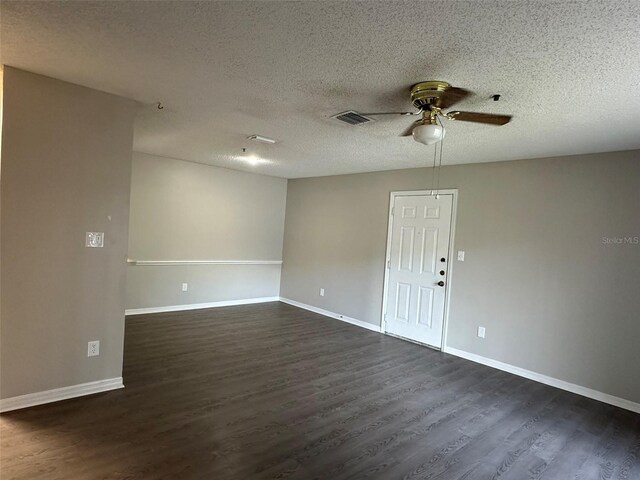 spare room featuring dark wood-type flooring, a textured ceiling, and ceiling fan