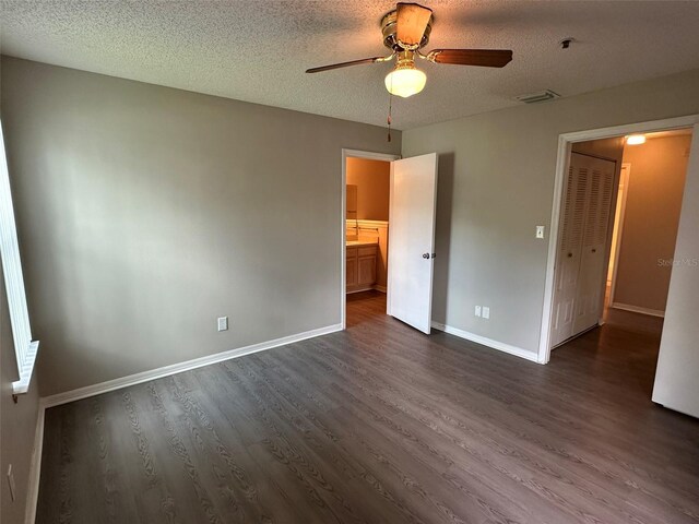 unfurnished bedroom with dark wood-type flooring, a textured ceiling, and ceiling fan