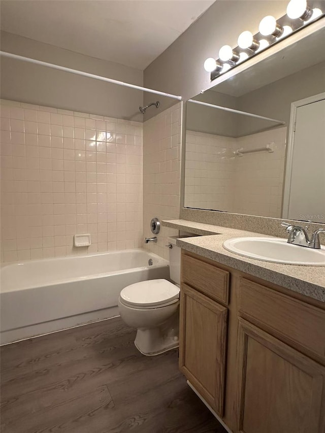 full bathroom with vanity, toilet, hardwood / wood-style floors, and tiled shower / bath