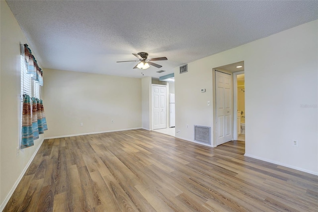 empty room with a textured ceiling, light hardwood / wood-style flooring, and ceiling fan