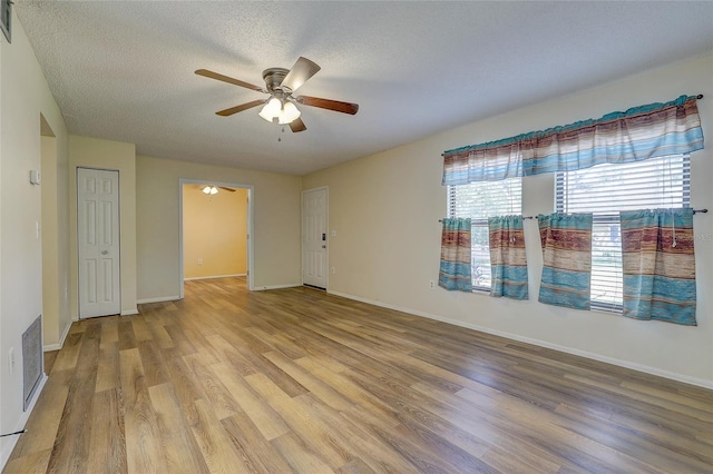 empty room with ceiling fan, a textured ceiling, and light wood-type flooring