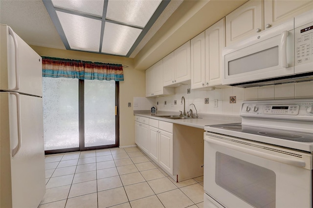 kitchen featuring white appliances, sink, light tile patterned floors, tasteful backsplash, and white cabinetry