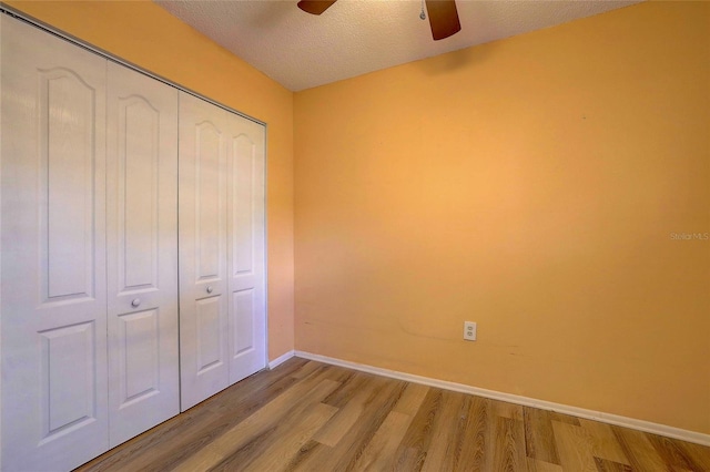 unfurnished bedroom featuring a textured ceiling, ceiling fan, light hardwood / wood-style flooring, and a closet