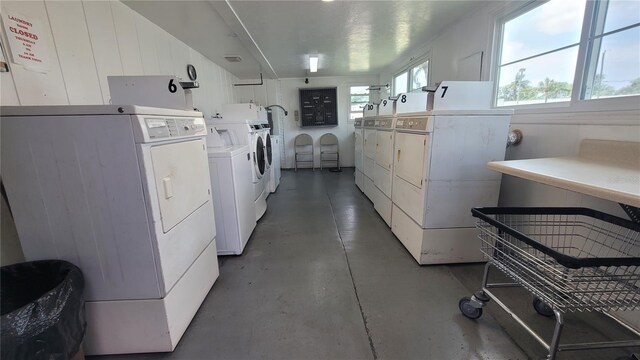 laundry room with washing machine and clothes dryer and wooden walls