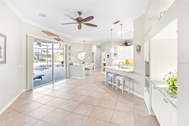 kitchen featuring decorative light fixtures, light stone counters, sink, ceiling fan, and a breakfast bar